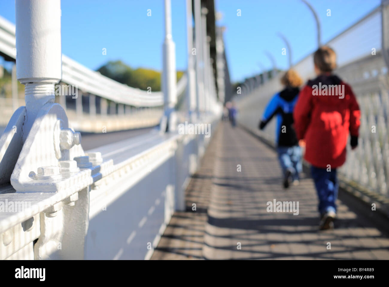 A fine sunny morning on Bristol`s famous Clifton suspension bridge with two unidentifiable children crossing the structure. Stock Photo